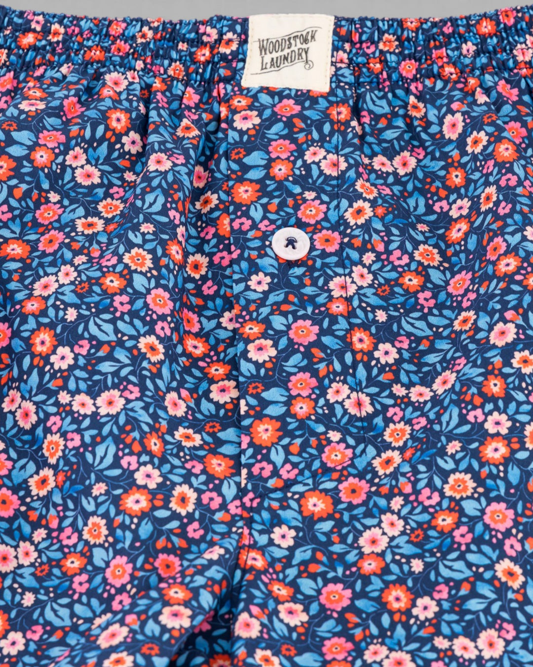 Macro view of the Dipsy floral pattern with pink and orange blossoms on a blue background.