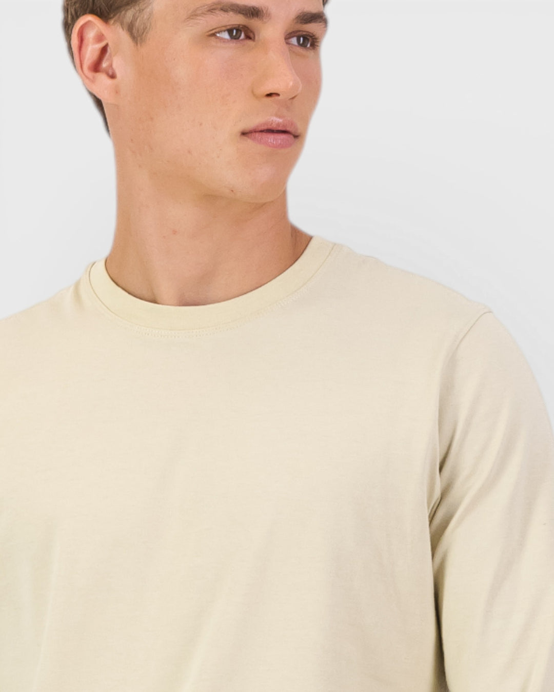 Man wearing a beige long-sleeve shirt against a plain background