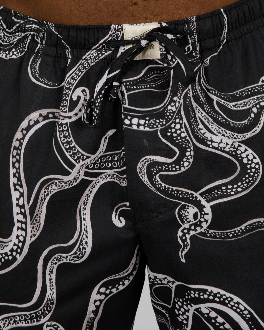 Drawstring waistband on thin black lounge pants with a white octopus print.