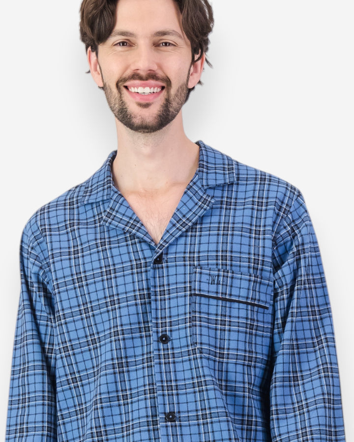 Man wearing a blue plaid flannel pyjama shirt against a white background