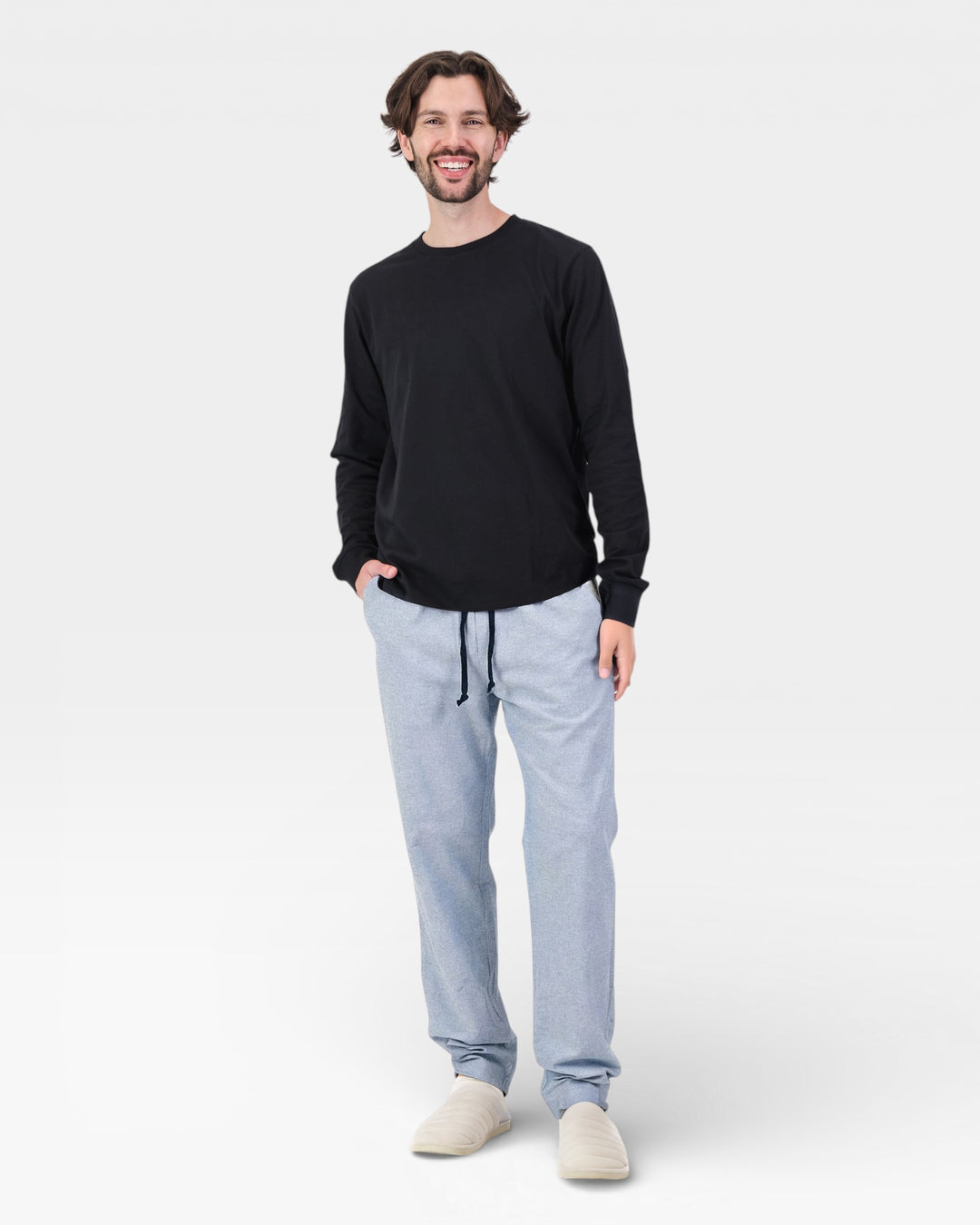 Man wearing a black long-sleeve shirt and light blue pants on a white background