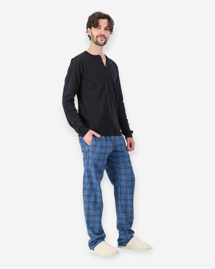 Man wearing a black long-sleeve shirt and blue plaid pajama pants on a white background