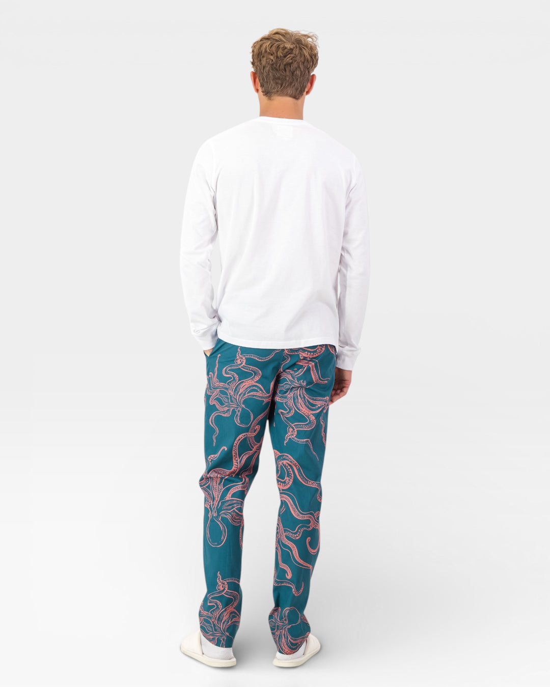 Man wearing a white long-sleeve t-shirt and green pants with pink octopuses on a white background