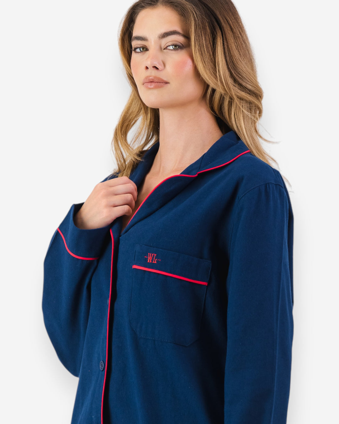 Woman wearing a navy blue flannel pyjama set with red piping on a white background