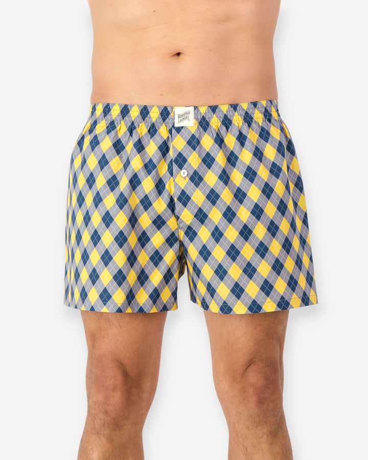 Yellow and blue checkered boxer shorts worn by a person on a white background